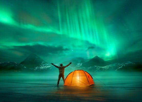 Un homme avec sa tente qui regarde les aurores boréales