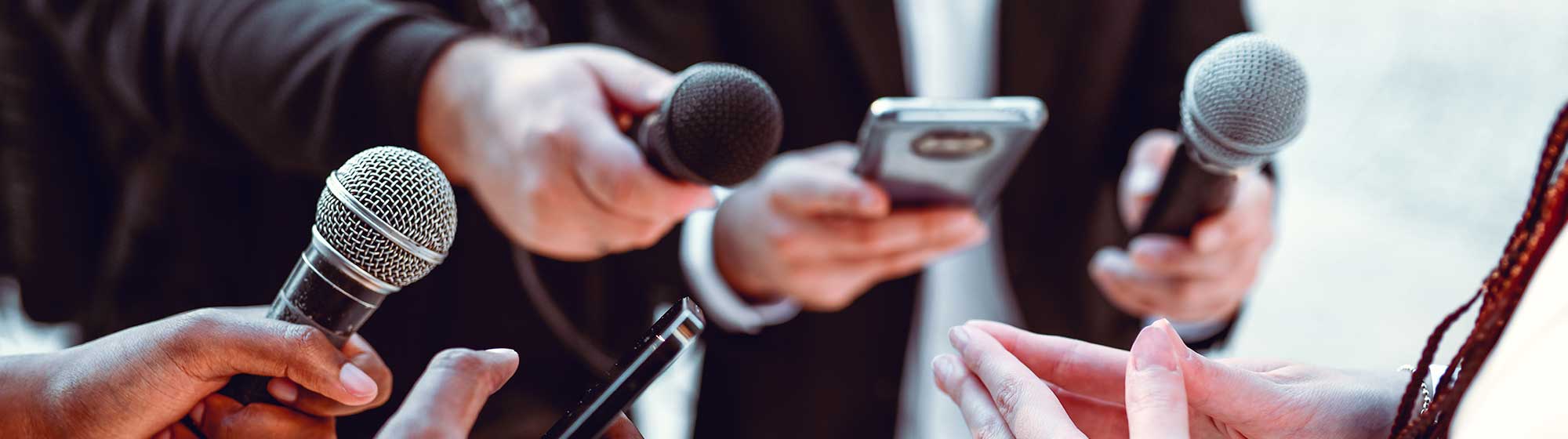 Plusieurs journalistes tendent leurs micros pour capter les paroles de la présentatrice