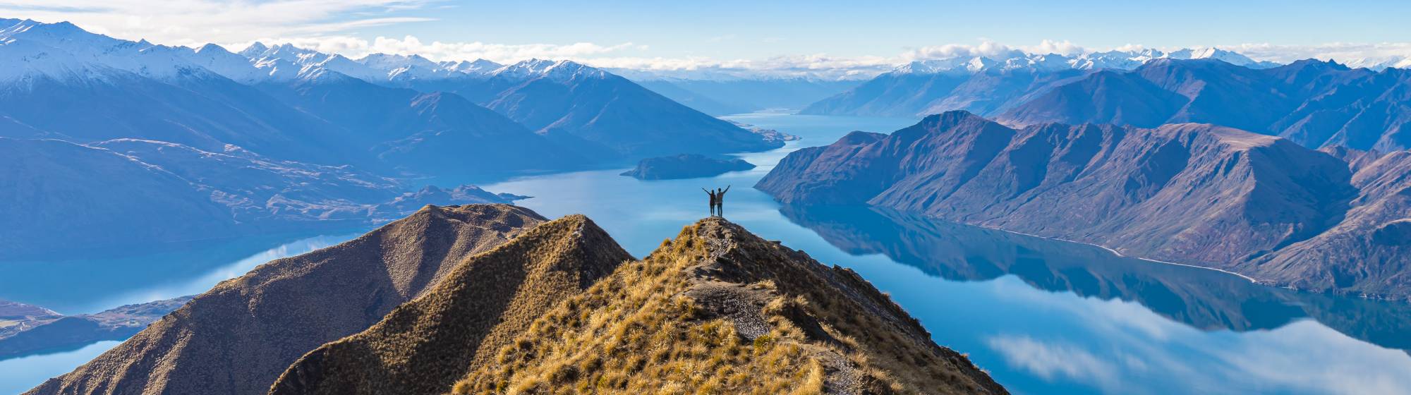 Deux randonneurs face  à l'immensité des montagnes et des lacs.