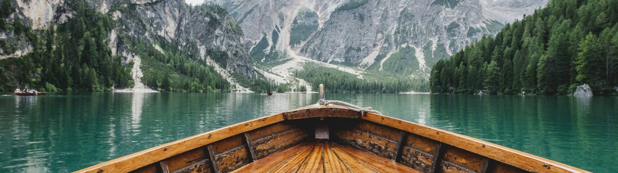 une barque en bois sur l'eau face à la montagne