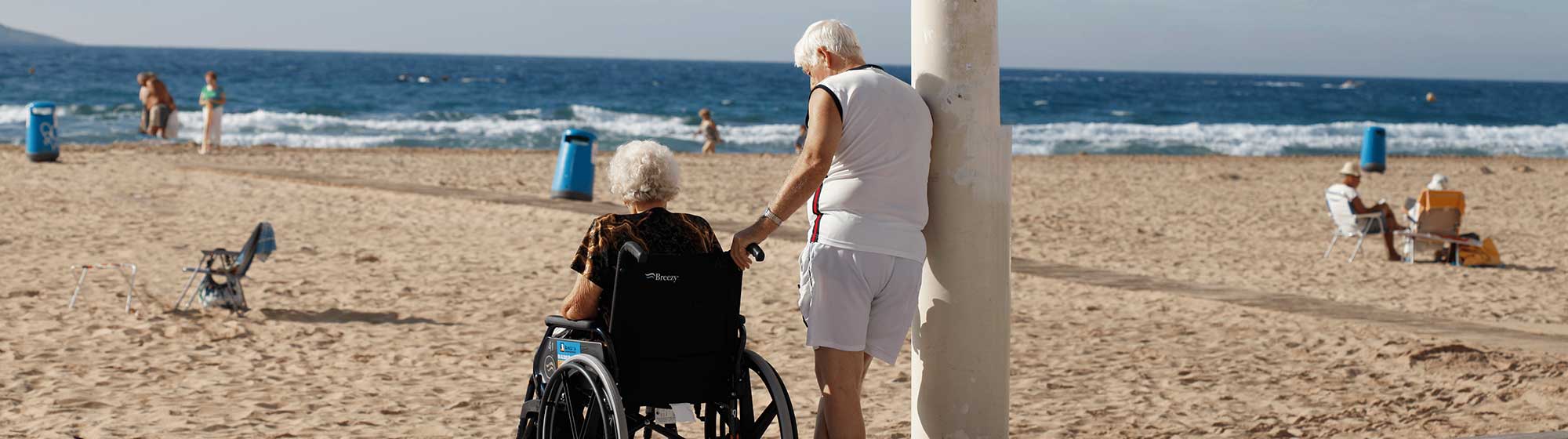 Deux personnes âgées contemplent l'horizon depuis le rivage d'une plage