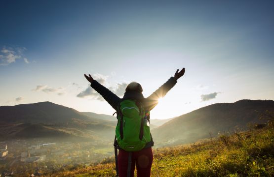 Une femme solo levant les bras devant un beau paysage. 