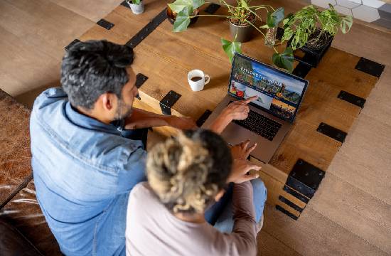Deux personnes sur un Pc, assis dans un canapé pour réserver leurs vacances.