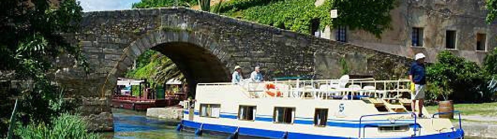 Une péniche traversant un pont dans un village. 