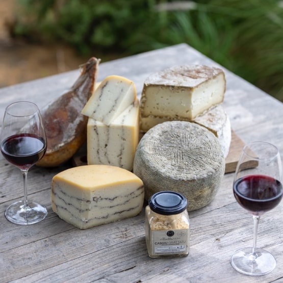 De nombreux fromages sur une table avec 2 verres de vin rouge