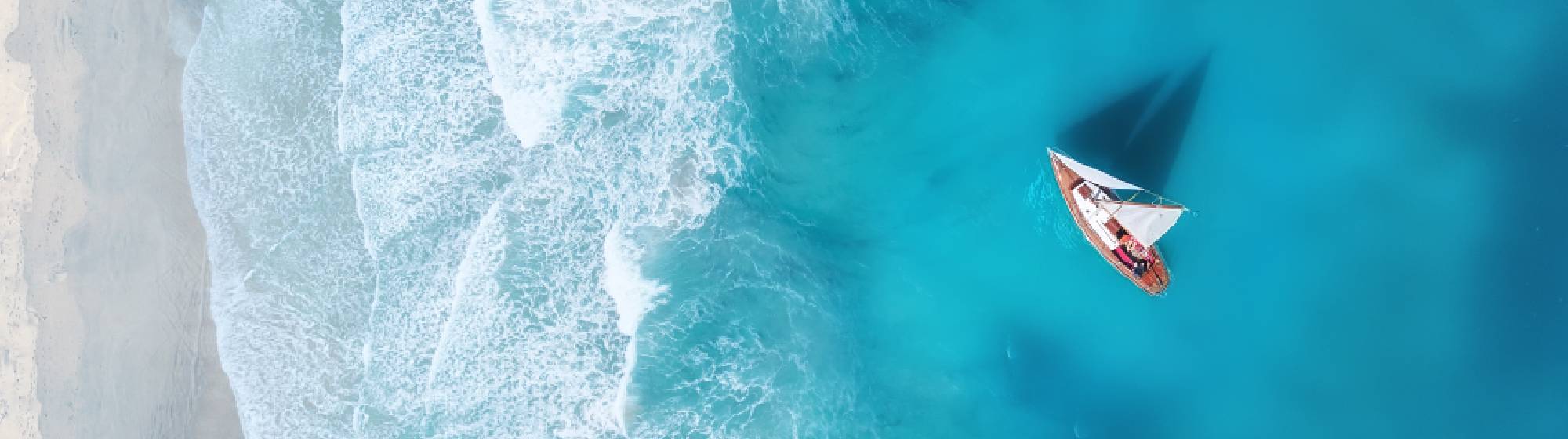 Un bateau naviguant sur une mer bleu turquoise proche d'une plage de sable fin. 