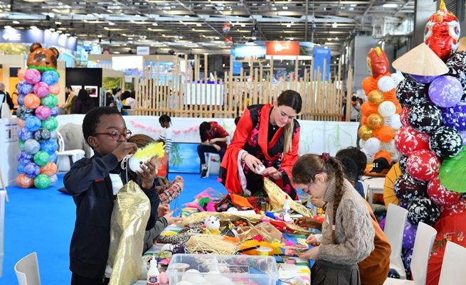 Une dame jouant avec des enfants sur l'espace enfants des Salons du TOURISME.
