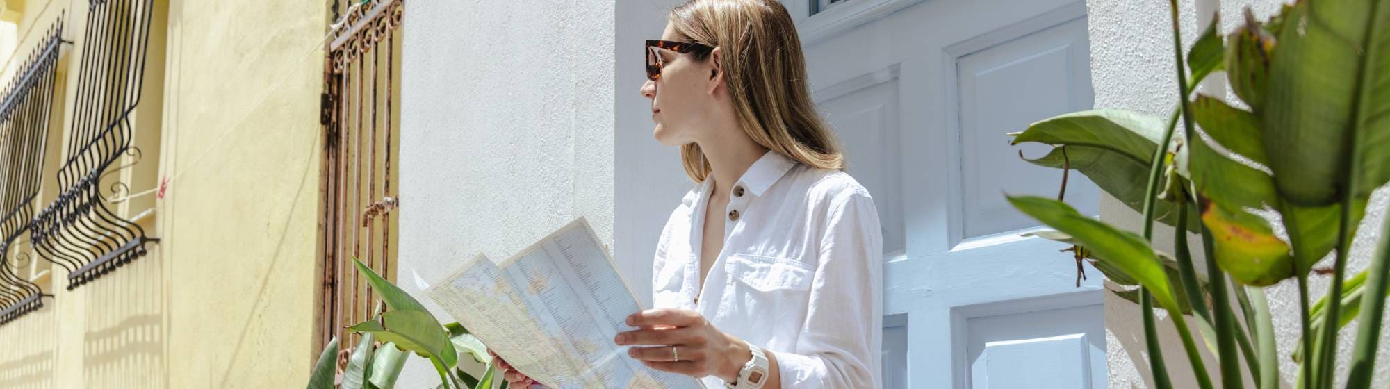 Personne assise sur les marches d’une maison, consultant une carte de voyage