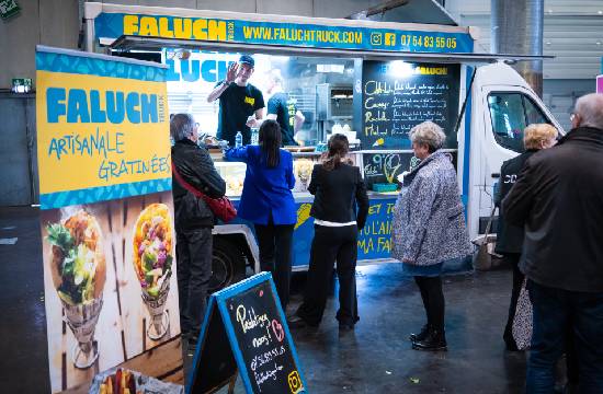 Des individus faisant la queue devant un foodtruck en attendant de pouvoir commander à manger.