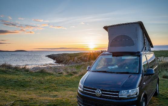 Van posé face à la mer devant un coucher de soleil. 