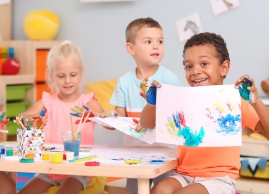 3 petits enfants font de la peinture et sourient