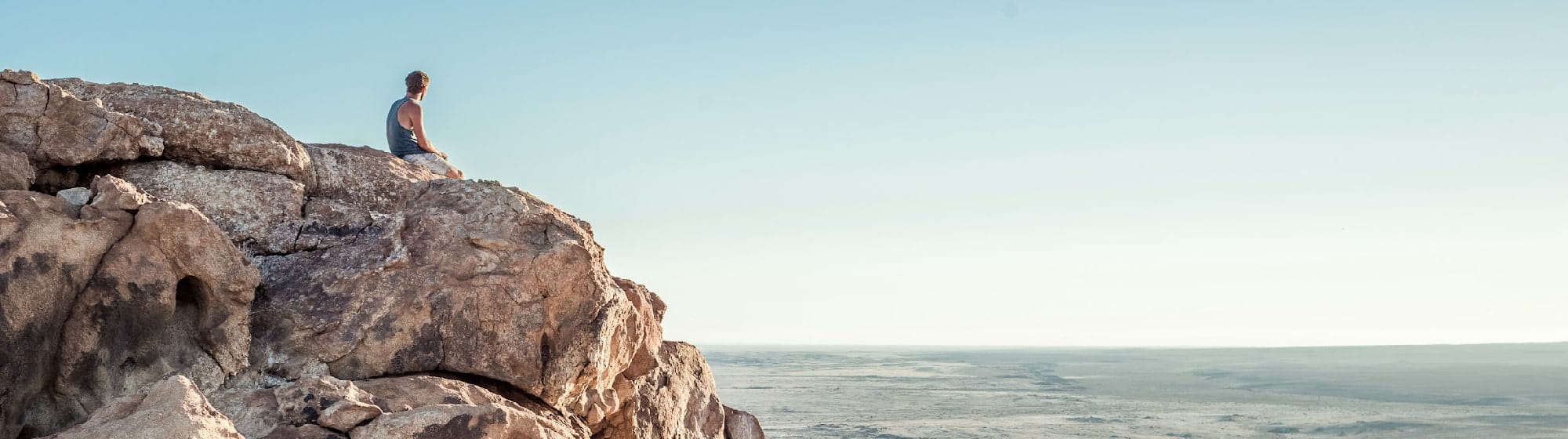 Un homme sur une falaise regardant la mer. 
