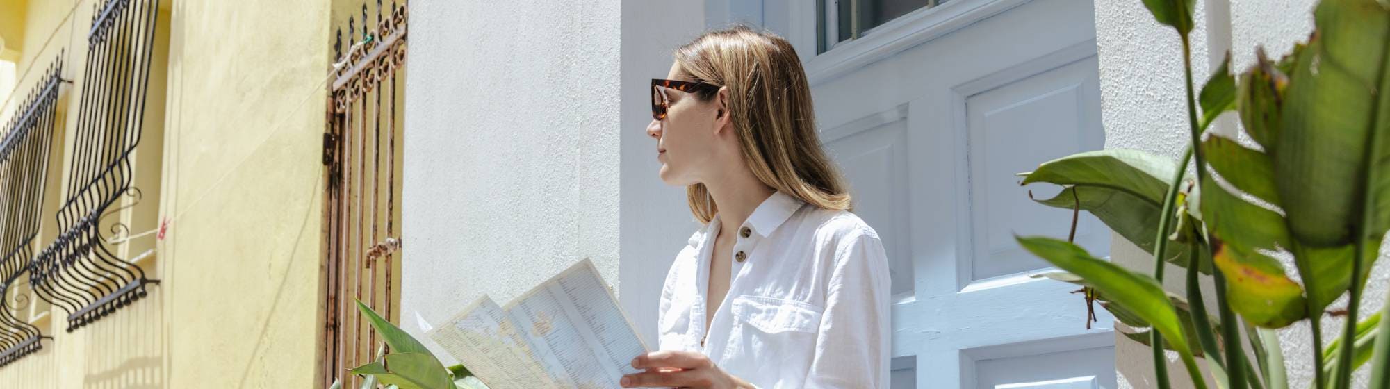 Personne assise sur les marches d’une maison, consultant une carte de voyage.