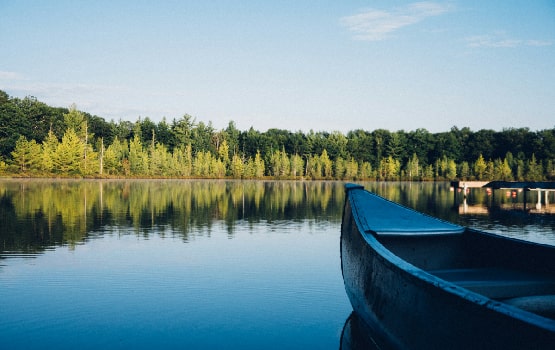 Une barque sur un lac entouré d'une foret.