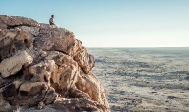 Un homme sur une falaise regardant la mer. 