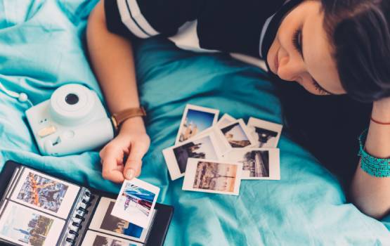 Une adolescente regarde ses photos de vacances et ses albums photos. 