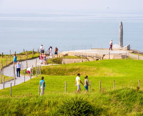 des personnes qui regardent une statue au bord de la mer