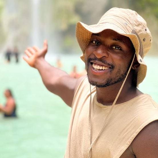 Un homme avec un chapeau devant une cascade. 