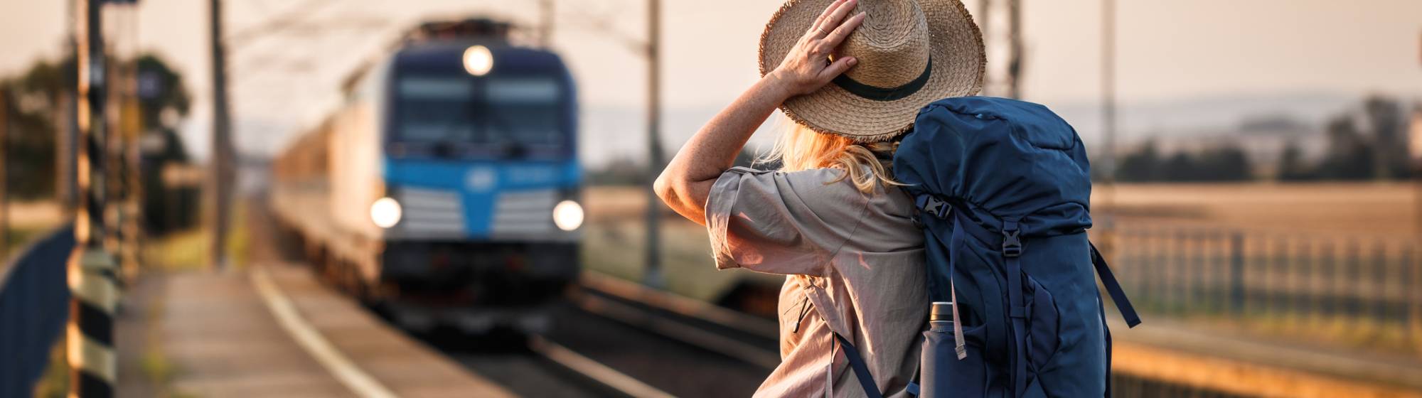 une femme qui tient son chapeau à l'approche du train