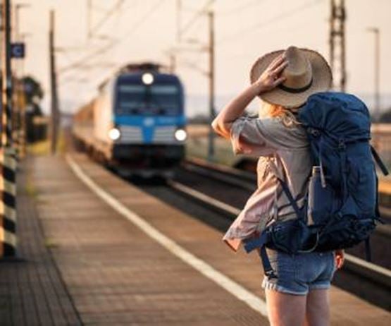 une femme qui tient son chapeau à l'approche du train