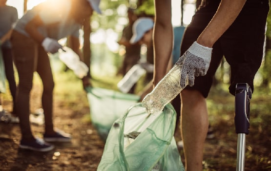 Des personnes ramassant des bouteilles pour les mettre dans des sacs plastiques.