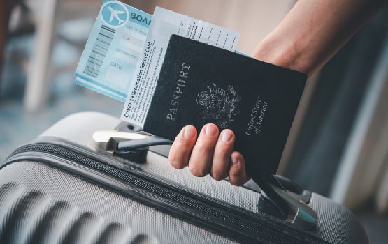 Image d'une main tenant un passeport et une valise.