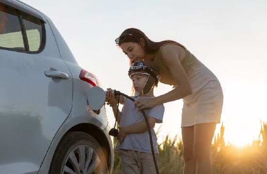 Un enfant aidant sa maman à recharger leur voiture éléctrique.