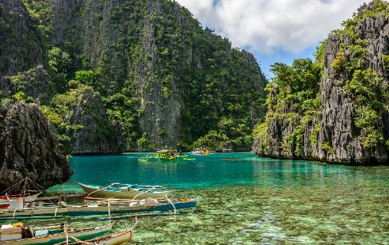 Photo de bateaux sur la mer au milieu de montagnes aux Phillipines.