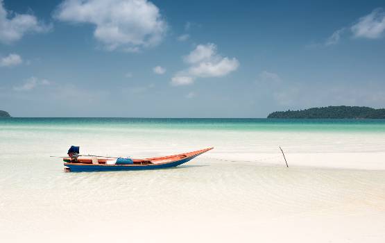 Bateau coloré échoué sur le sable d'une plage paradisiaque.