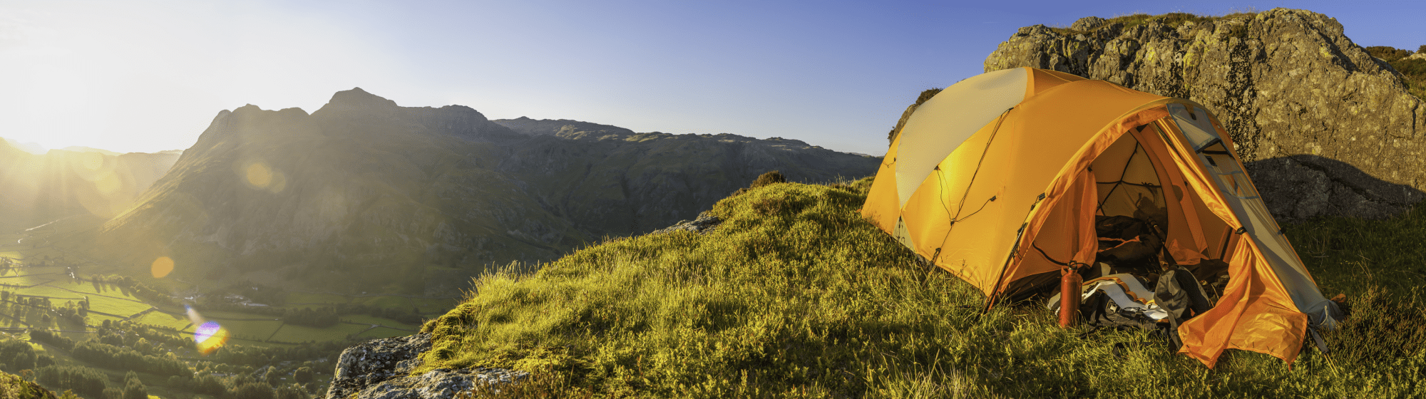 Tente en haut de la montagne surplombant la vallée du coucher du soleil
