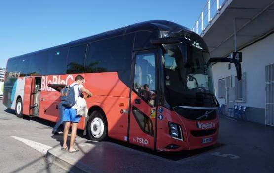 Voyageur montant dans un autocar rouge avec ses bagages