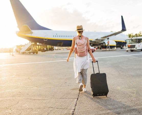 une femme avec une valise qui va monter dans un avion