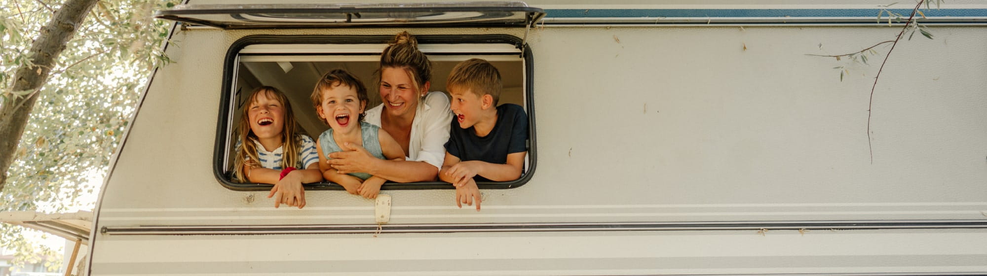 3 enfants et leur maman qui regardent par la fenêtre du camping-car