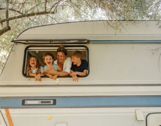 3 enfants et leur maman qui regardent par la fenêtre du camping-car