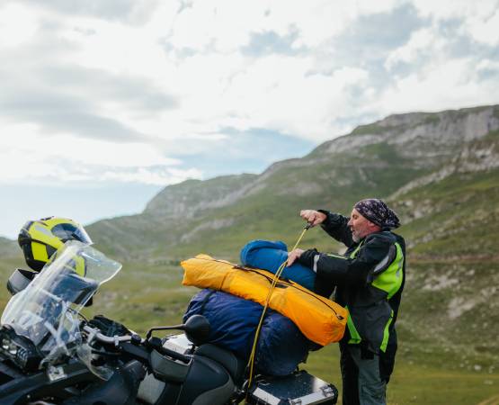 un homme qui prépare ses bagages sur sa moto